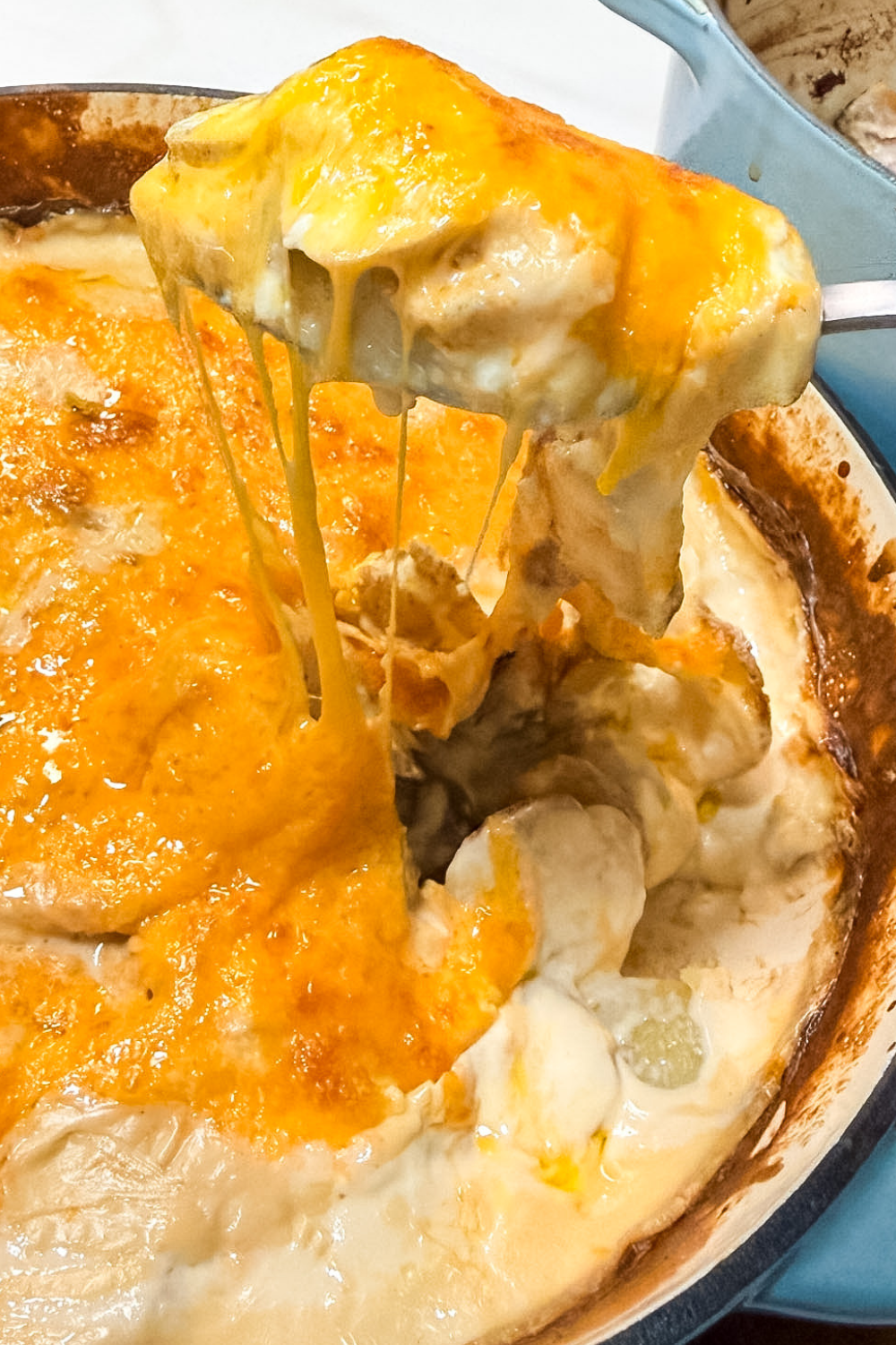 serving cheesy potatoes au gratin with melted cheese stretch