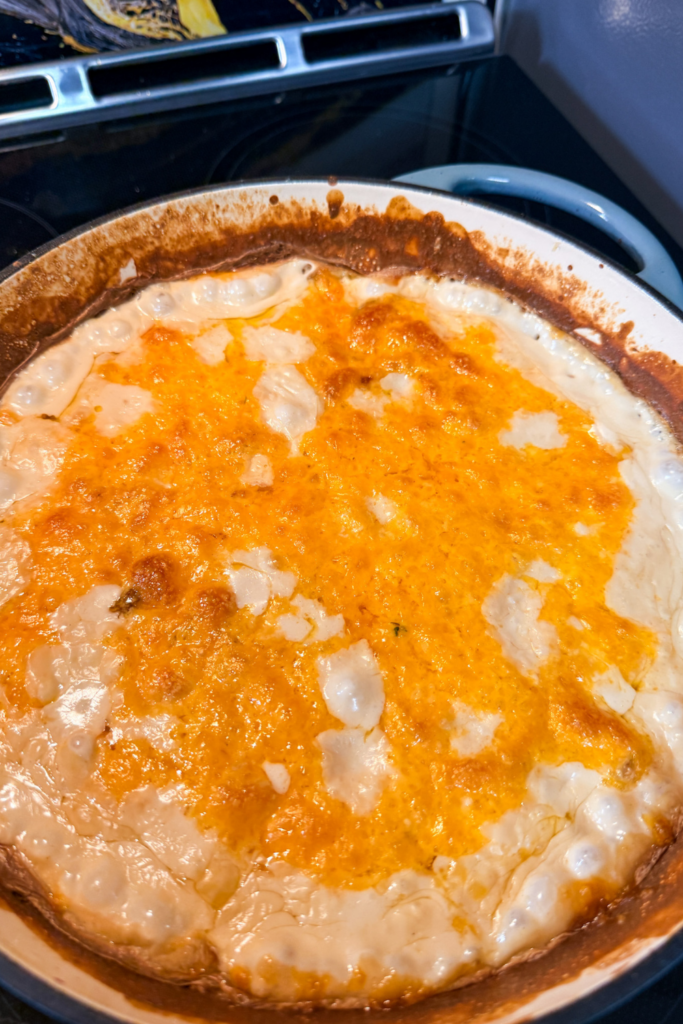 golden melted cheese on creamy potatoes au gratin in cast iron pan