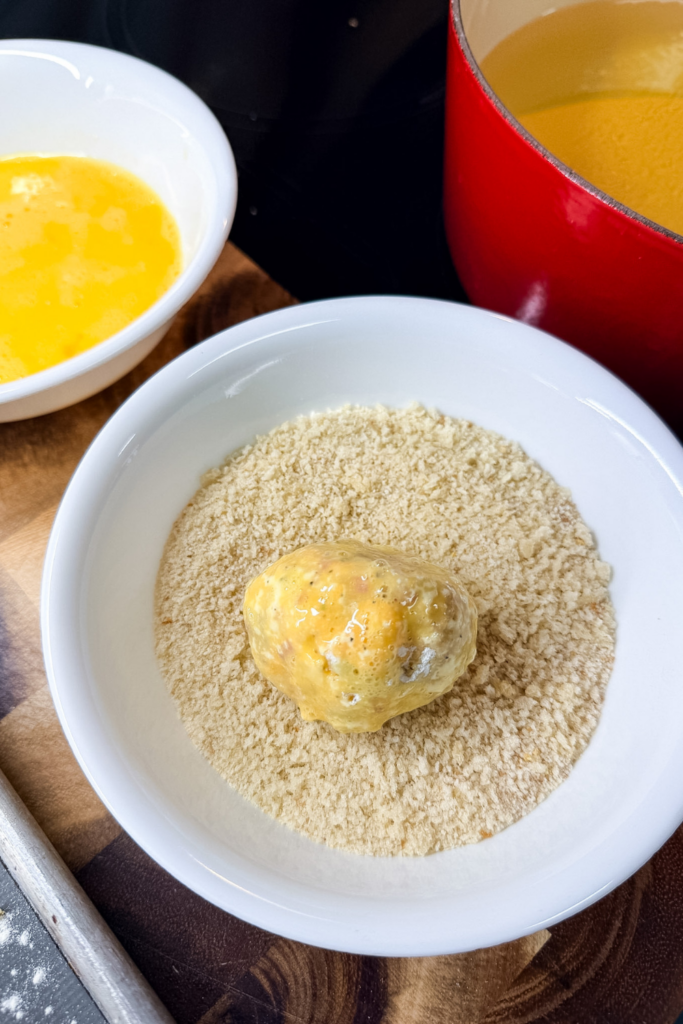 Coating ham croquette in breadcrumbs for crispy exterior