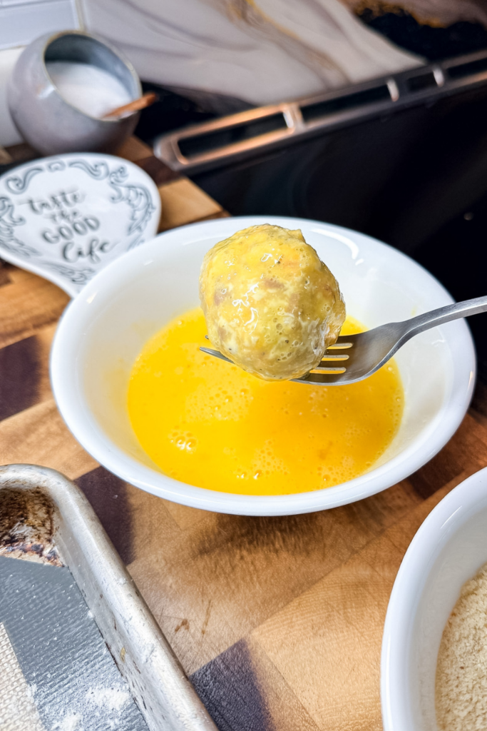 Dipping ham croquette in egg wash before breading