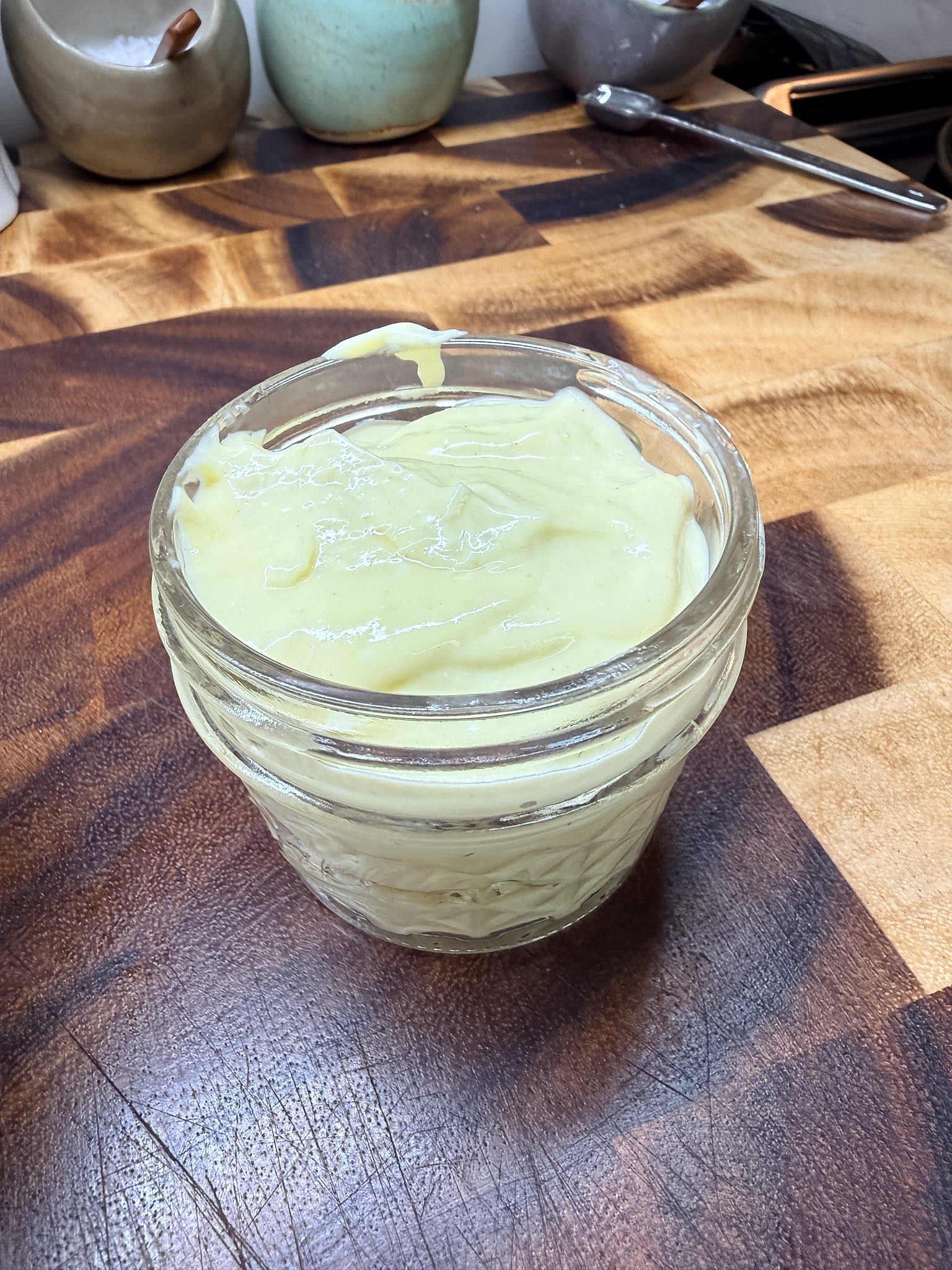 Homemade garlic aioli made with whole egg and neutral oil in glass jar.