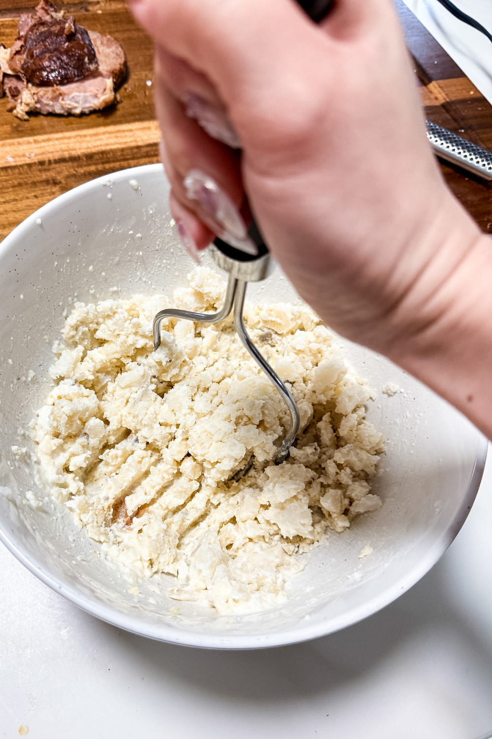 Mashing baked potatoes in a bowl for ham croquettes