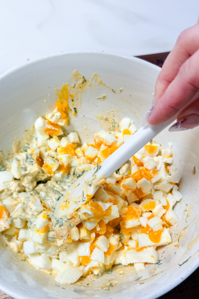 Mixing chopped eggs into herb mayonnaise dressing