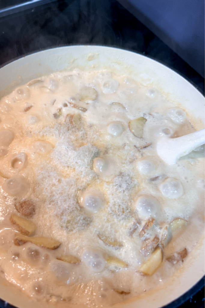 creamy potato gratin sauce bubbling and thickening on stovetop