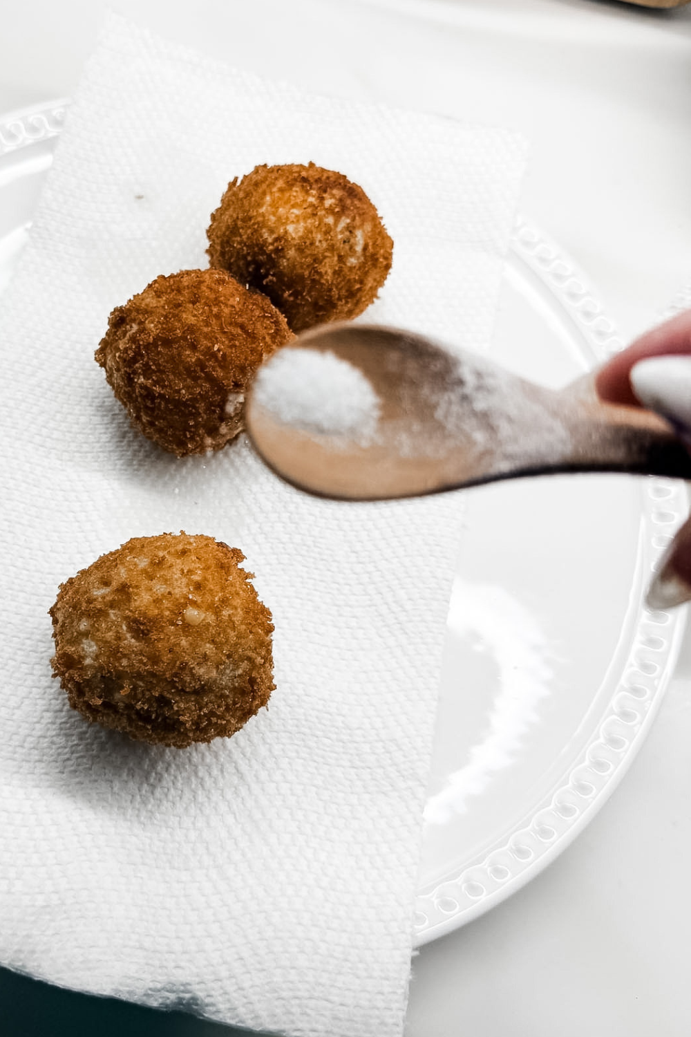Sprinkling salt on freshly fried ham croquettes