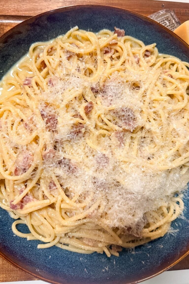 Plate of spaghetti carbonara topped with grated Romano cheese