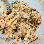 Salmon salad mixed with herbs, celery, and shallots in a bowl