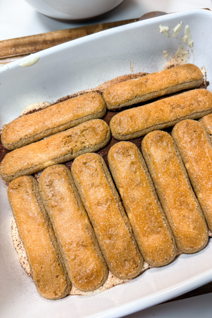 Layer of espresso-soaked ladyfingers in baking dish for tiramisu