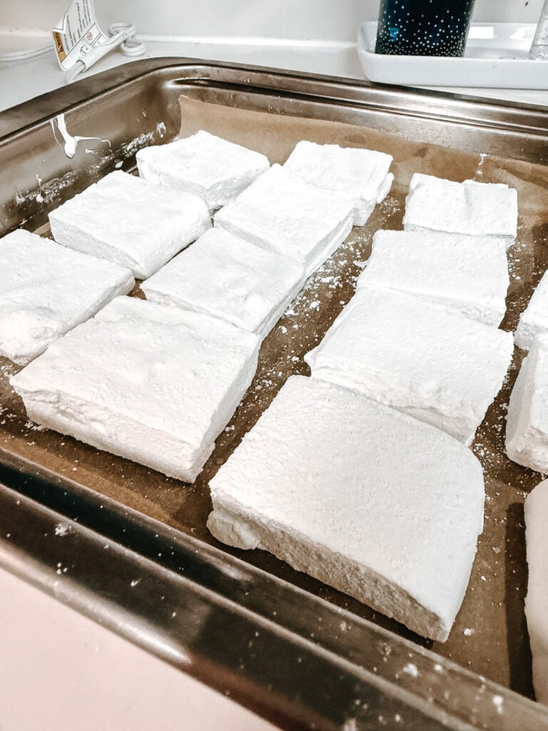 Finished homemade marshmallow squares coated in powdered sugar arranged on a baking sheet