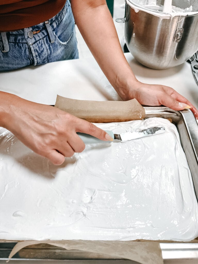 Smoothing freshly poured marshmallow mixture in a baking pan with an offset spatula