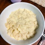 Creamy homemade mac and cheese with farfalle pasta served in a white bowl, silky white cheese sauce coating every noodle — mac and cheese from scratch