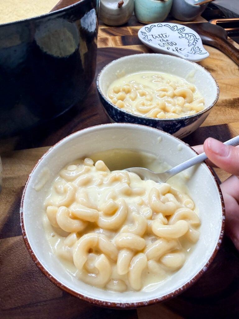 Close-up of creamy mac and cheese with wooden spoon, showing the silky, smooth sauce